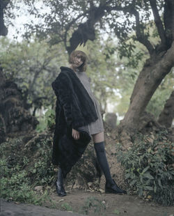 Full length of woman standing amidst trees in forest