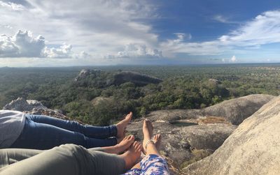 Low section of man relaxing on landscape against sky