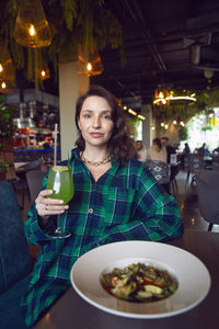 Portrait of young woman having food at restaurant