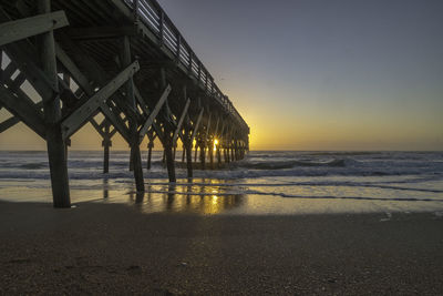 Pier over sea against sky during sunset