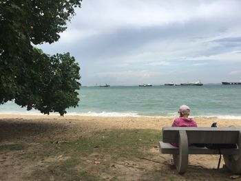 Rear view of woman on beach against sky