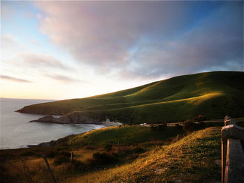 Scenic view of landscape by sea against sky