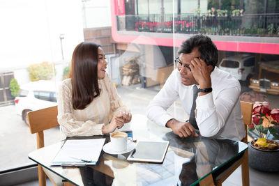 Young woman using phone while sitting on table
