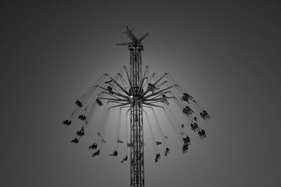 Low angle view of chain swing ride against sky