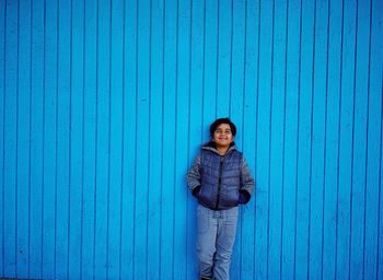 Portrait of woman standing against blue wall