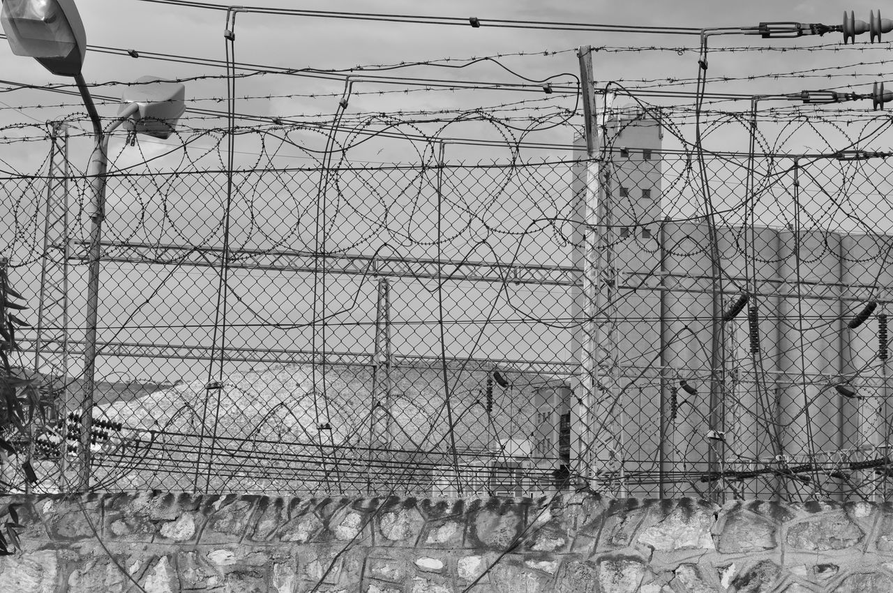 fence, boundary, barrier, metal, no people, barbed wire, safety, day, security, protection, sky, outdoors, architecture, nature, wire, chainlink fence, razor wire, pattern, built structure, field, power supply