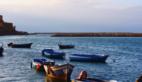 Boats in sea against cloudy sky