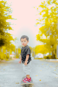 Cute boy looking away while standing on yellow toy