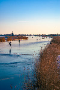 Ice skaters on a frozen dutch canal on a winter afternoon