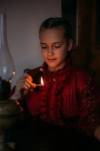 Cute girl holding burning matchstick at home
