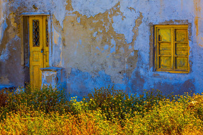 Old blue house facade with yellow window and yellow door, santorini.
