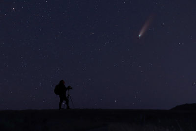 Silhouette man standing on field against sky at night