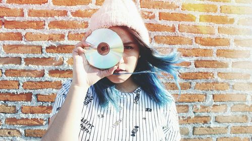 Young woman standing against brick wall