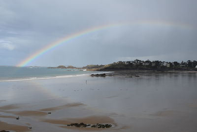 Scenic view of rainbow over sea against sky