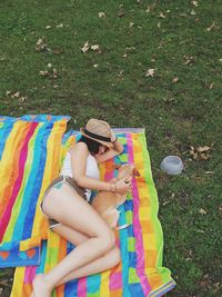 High angle view of woman lying with dog on picnic blanket at park