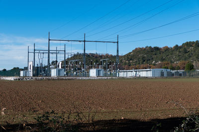 Electrical substation in field against blue sky