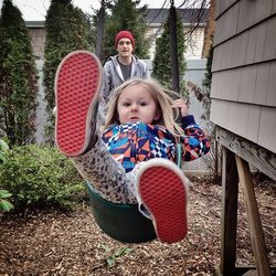 Portrait of girl swinging with father standing in background