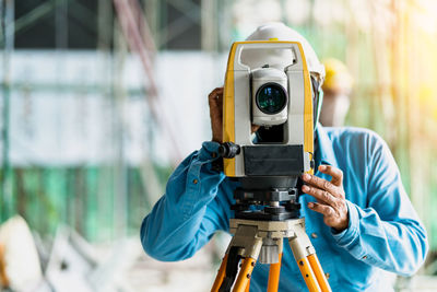 Engineer looking through theodolite at construction site