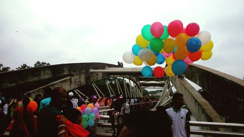 People on multi colored balloons against sky