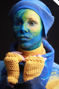 Close-up of young woman with painted face against black background