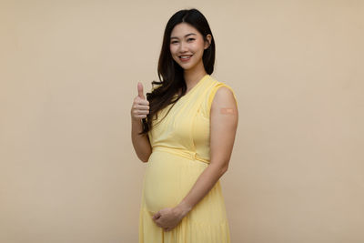 Portrait of a smiling young woman against gray background