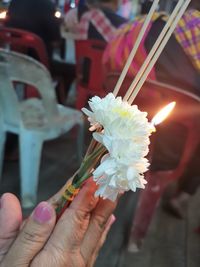 Close-up of hand holding incense stick with flower