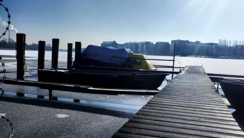 Boats moored at harbor against sky in city