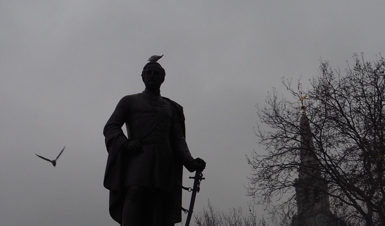 low angle view, statue, human representation, sculpture, sky, no people, outdoors, bird, day