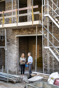 Full length portrait of a young couple standing at construction site