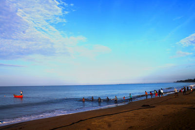 People on beach against blue sky