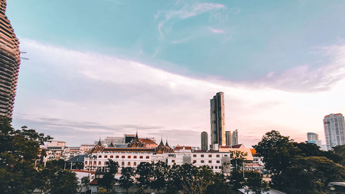 Buildings in city against cloudy sky