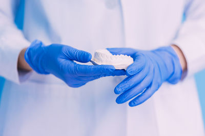 Midsection of dentist holding dentures in hospital