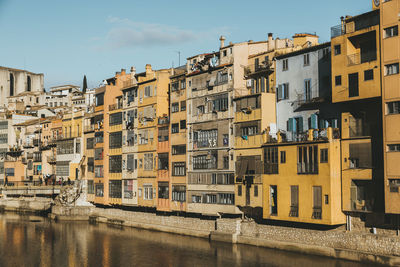 Buildings by river against sky