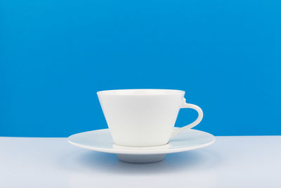 Coffee cup on table against blue background