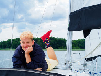 Handsome person laying on yacht deck and enjoying on a sailing yacht on summer vacations person