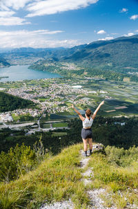 Woman with arms raised on mountain against sky