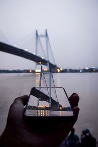 Low angle view of person hand on sea against sky