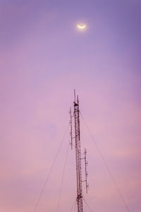 Low angle view of electricity pylon against sky during sunset