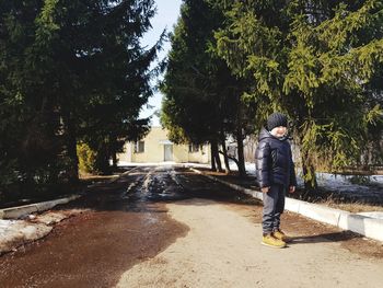 Rear view of man standing on road amidst trees