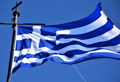 Low angle view of flags against clear blue sky