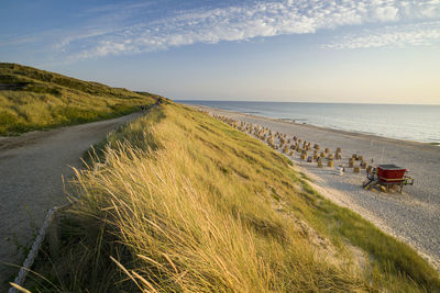 Scenic view of road by sea against sky