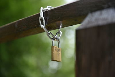Close-up of padlock hanging to chain on railing