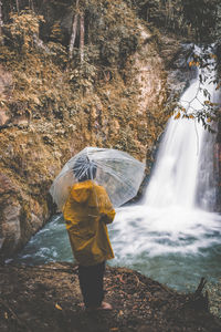 Rear view of man standing by stream