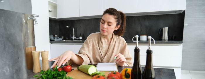 Young woman using mobile phone while sitting on table