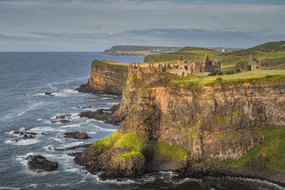 Dunluce castle illuminated by sunlight, perched on the edge of cliff, northern ireland