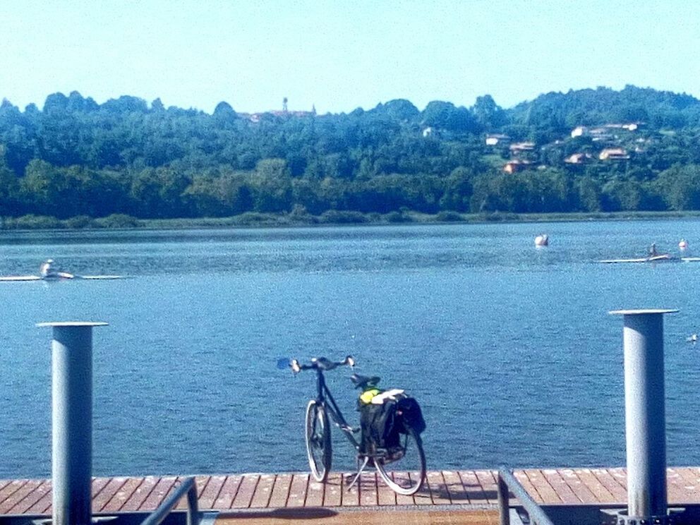 BICYCLES ON PIER OVER LAKE AGAINST SKY