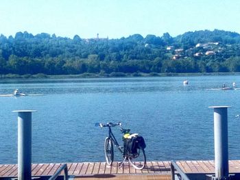 Bicycle on pier by lake against sky