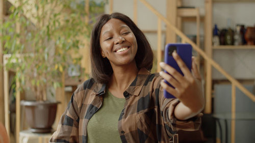 Portrait of young woman using mobile phone while standing in cafe