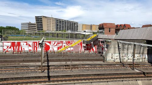 Graffiti on railroad tracks by buildings in city against sky