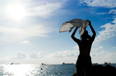 Low angle view of silhouette woman in sea against sky